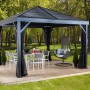Anthrazitfarbener Sojag Pavillon South Beach 12x12 mit Vorhängen und Gartenmöbeln auf einer Holzterrasse.
