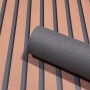 Schwarze Marburg Vliestapete GZSZ Textiloptik Uni mit Rolle vor Wand mit Streifenmuster.