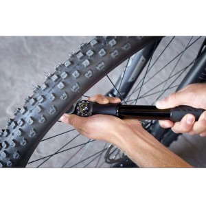 Schwarze Topeak Mountain DAG Handpumpe mit Manometer pumpt einen MTB-Reifen auf. Ideal für Fahrradreifen.