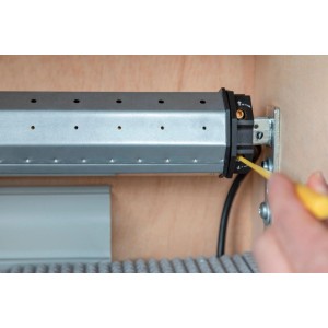 Silberner Schellenberg Rollladenmotor Standard Mini 6 Nm, Endlageneinstellung mit gelbem Einstellstift im Holzkasten.