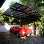 Schwarzes Ximax Alu Carport Portoforte mit transparentem Dach und rotem Auto.