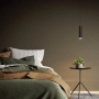 Moderne LUXULA Hängelampe in Schwarz-Gold über Nachttisch im Schlafzimmer.
