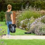 Frau trägt Bosch Mähroboter Indego XS 300 durch den Garten.