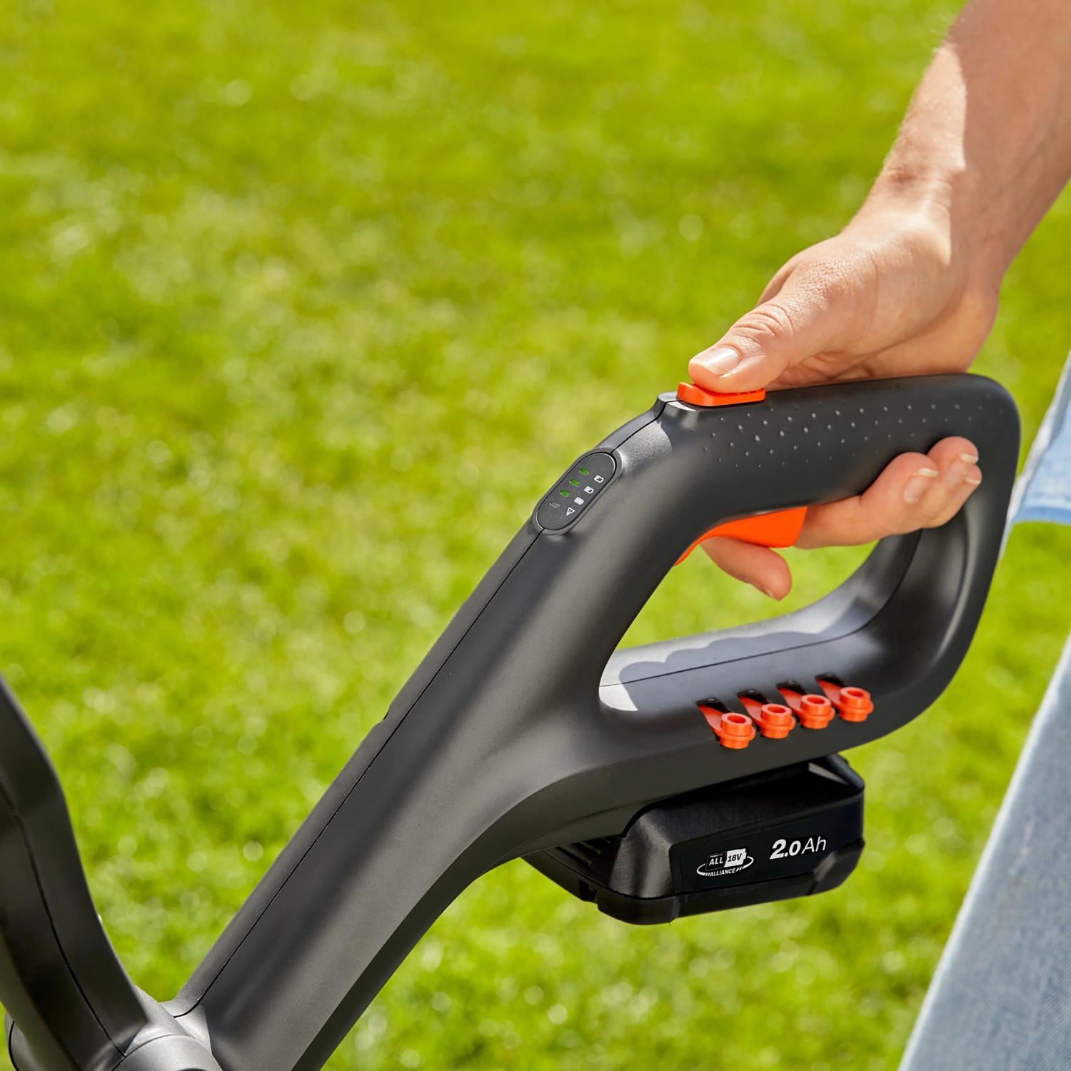 Gardena Akku-Trimmer EasyCut 23/18V: Detailaufnahme von Griff und Akku vor Rasen.