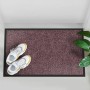 Lila Schmutzfangmatte Rhine 90x600cm mit Schuhen und Pflanze im Eingangsbereich.