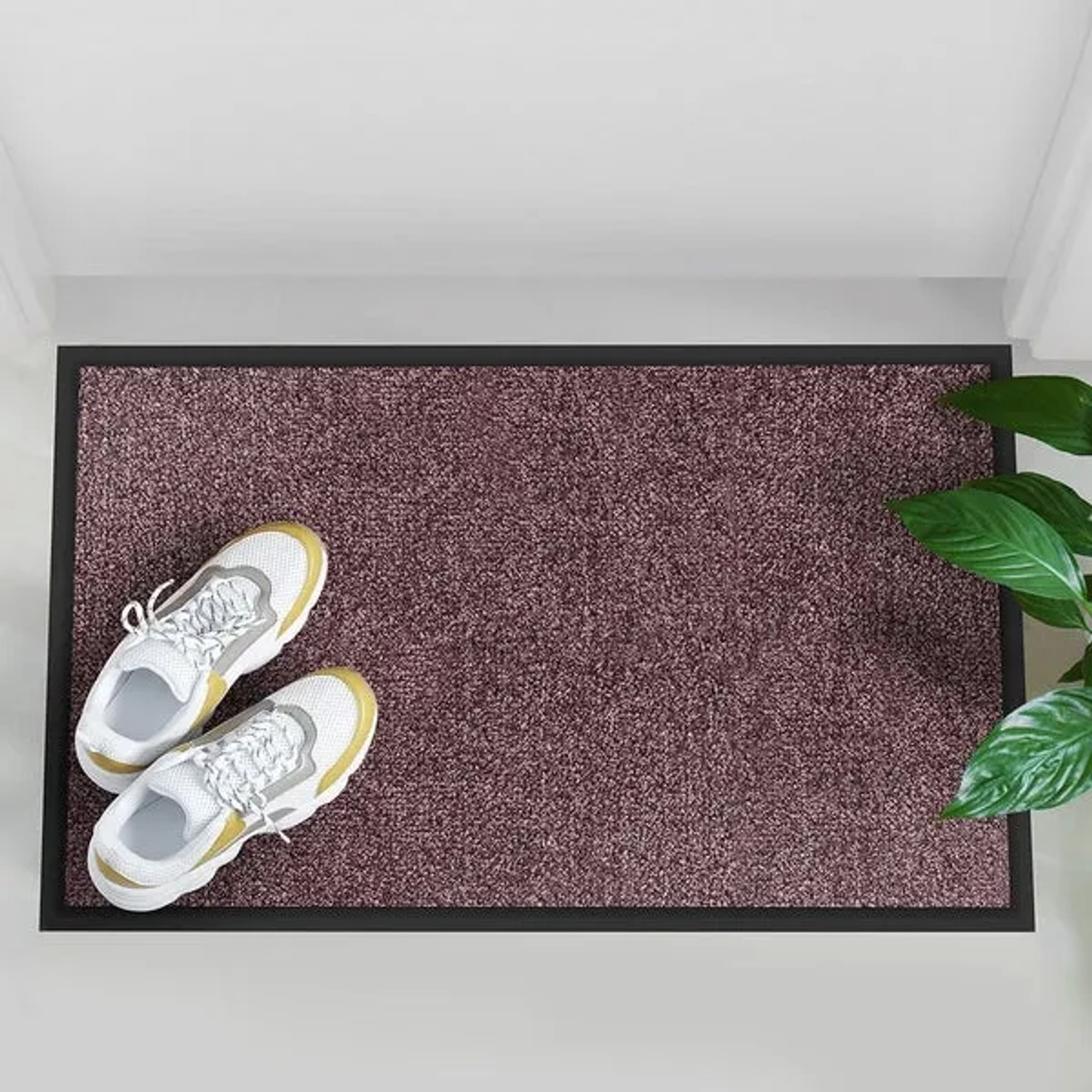 Lila Schmutzfangmatte Rhine 90x600cm mit Schuhen und Pflanze im Eingangsbereich.