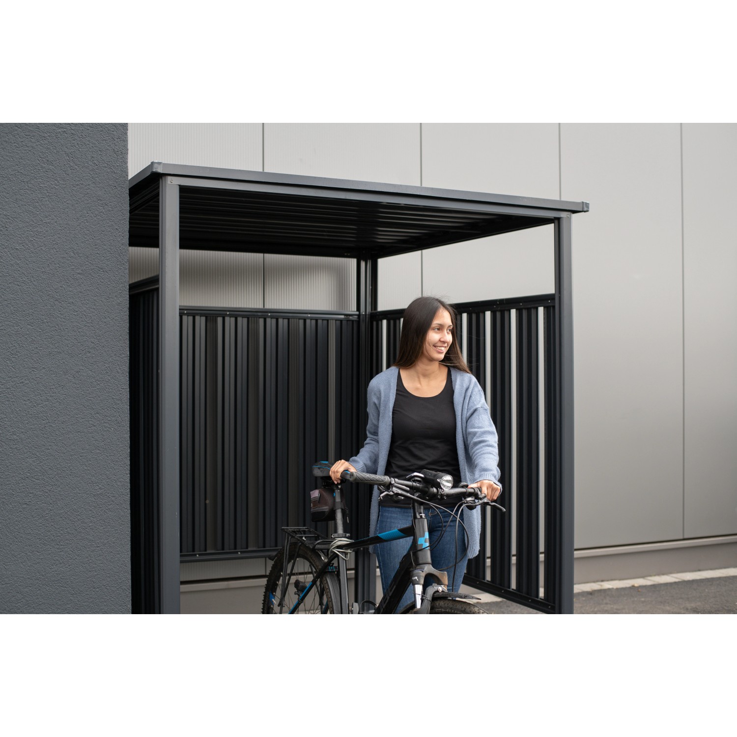 Anthrazitfarbener Westmann Fahrradunterstand mit Fahrrad und Person. Ideal als Terrassenüberdachung.