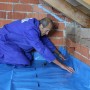 Mann verlegt EPS Dachboden-Dämmplatte (120mm) auf einem Dachboden mit Ziegelwand.