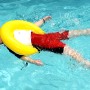 Kind mit gelbem Freds Swim Academy Schwimmreifen im Wasser. Schwimmhilfe für Kinder von 4-8 Jahren.