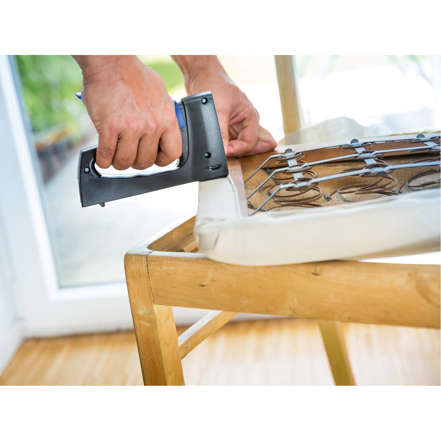Feindrahtklammern: Hand tackert Polster mit LUX Feindrahtklammern auf Holzstuhl.