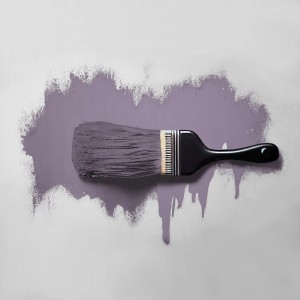 Pinsel mit matter violetter Wandfarbe Dunkellavendel auf heller Fläche. Farbtropfen sichtbar.