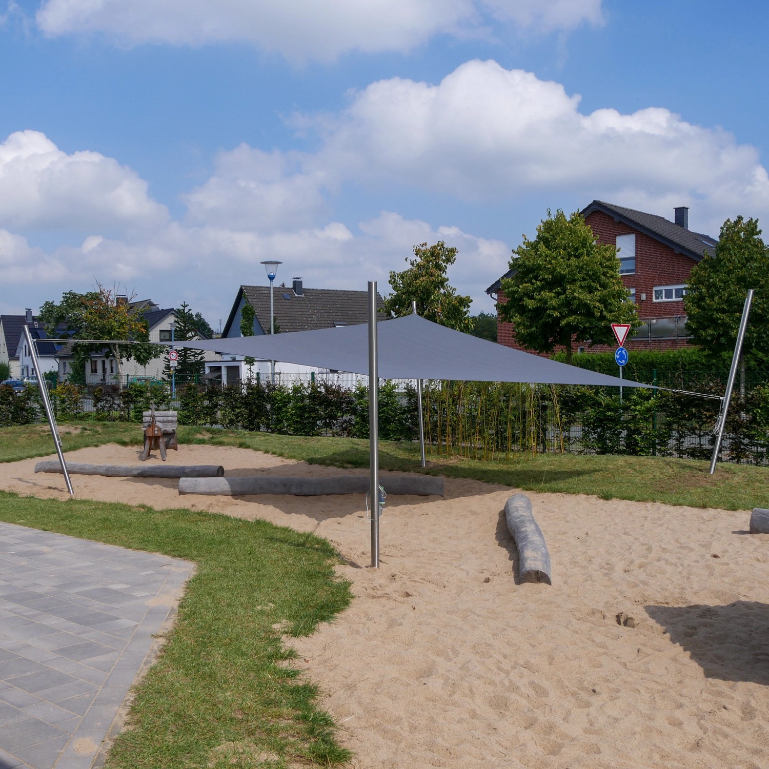Anthrazitfarbenes Toldoro Sonnensegel Dreieck (4x4x4m) über Sandkasten im Garten.