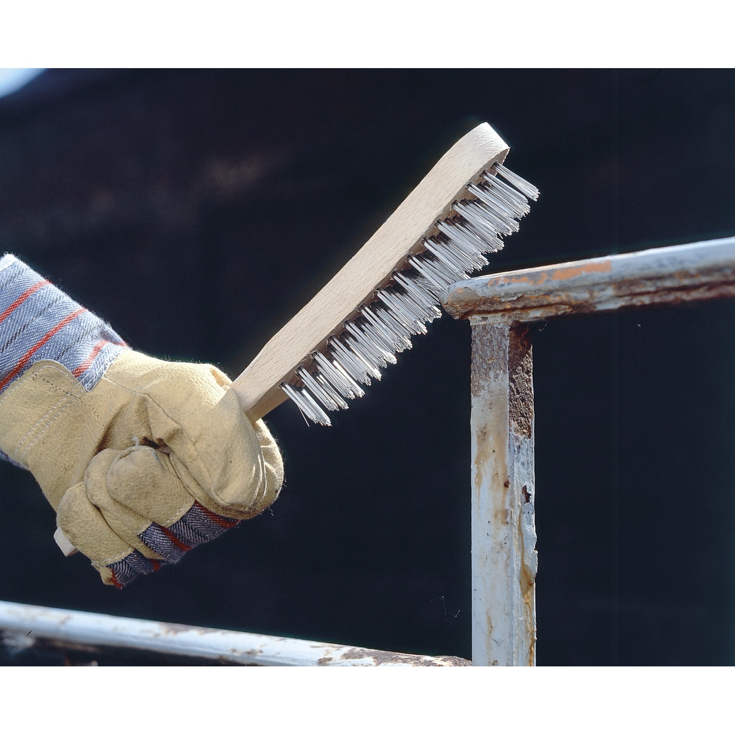 Hand mit LUX Drahtbürste (4-reihig, rostfrei) beim Entrosten von Metall.