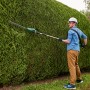 Mann schneidet hohe Hecke mit Bosch Akku-Teleskop-Heckenschere UniversalHedgePole 18 Solo.