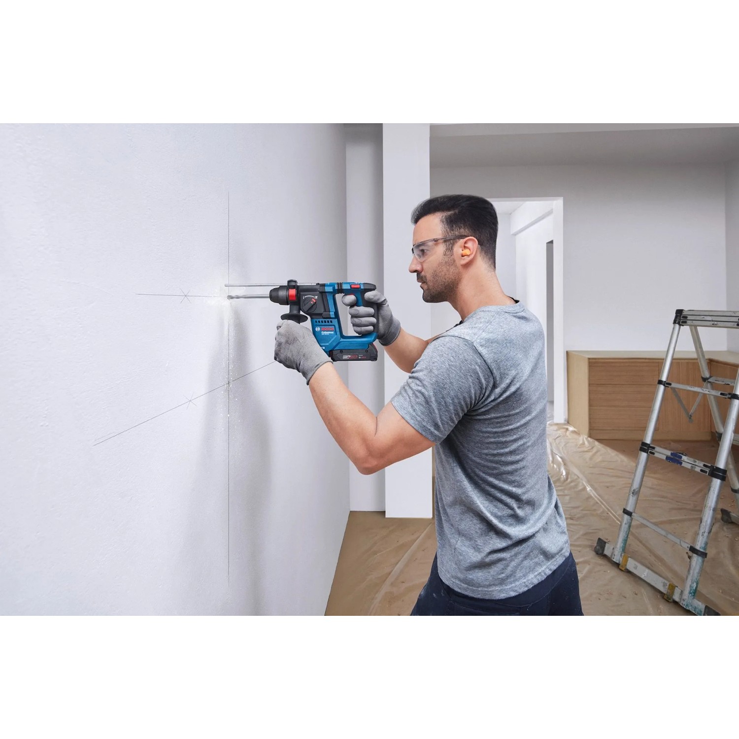 Mann bohrt mit Bosch Akku-Bohrhammer GBH 18V-18 ein Loch in die Wand.