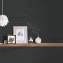 Vliestapete Trendwall 2 Uni Schwarz an Wand mit Deko-Elementen auf Holzregal.