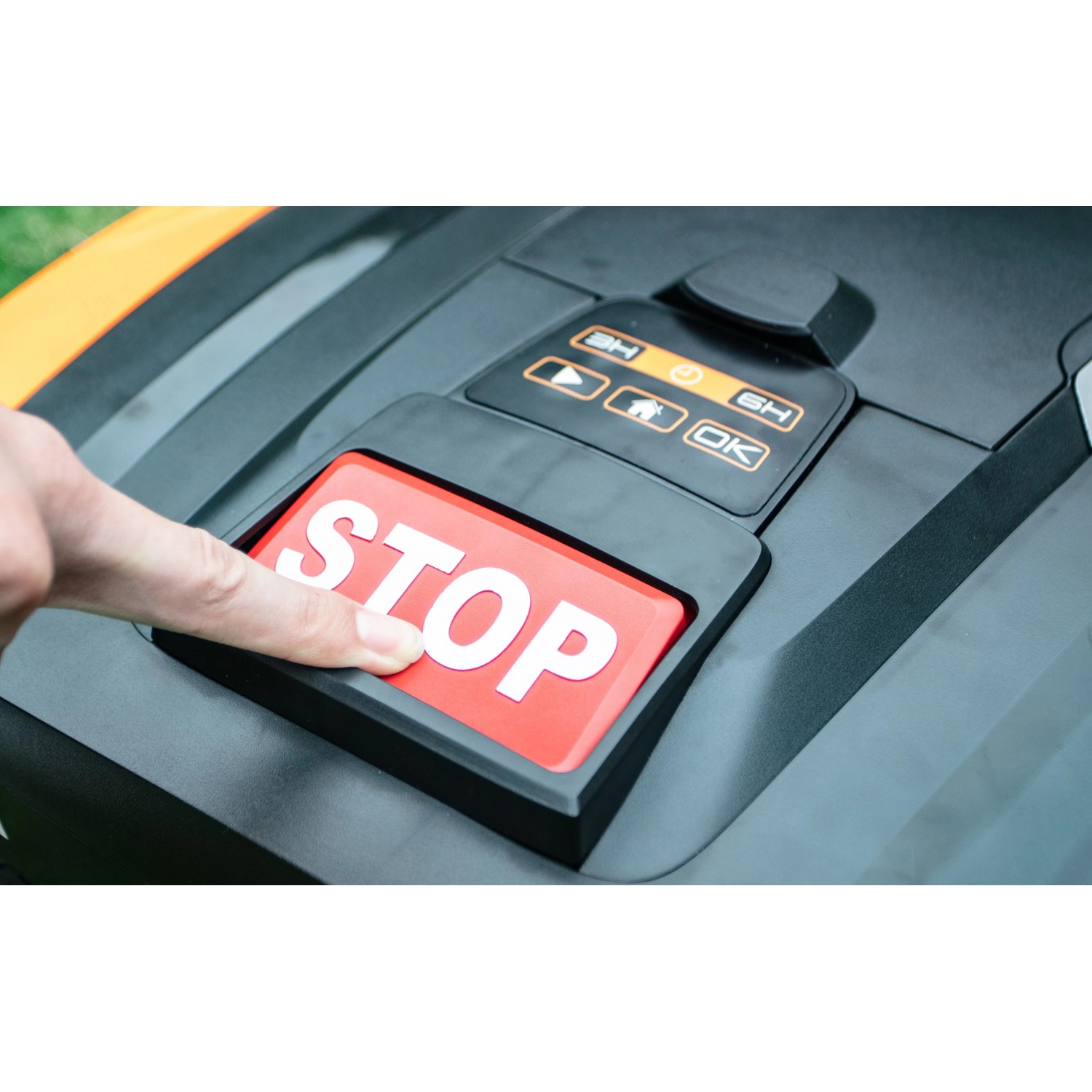 Hand drückt rote Stopptaste auf Yard Force EasyMow 260B Mähroboter.