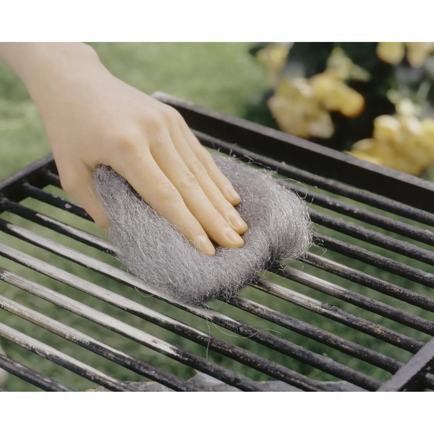 Hand reinigt Grillrost mit LUX Stahlwolle Feinheit 5. Schleifmittel zur Reinigung.