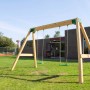 Freistehende Doppelschaukel aus Kiefernholz mit grünen Schaukelsitzen auf einer Wiese.