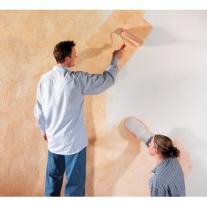 Mann streicht Wand mit Farbroller, Frau mit LUX Kreativ-Handschuh für Lasurtechnik.