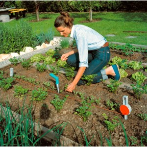 Frau benutzt Gardena Pflanzer im Gartenbeet zum Pflanzen von Setzlingen.