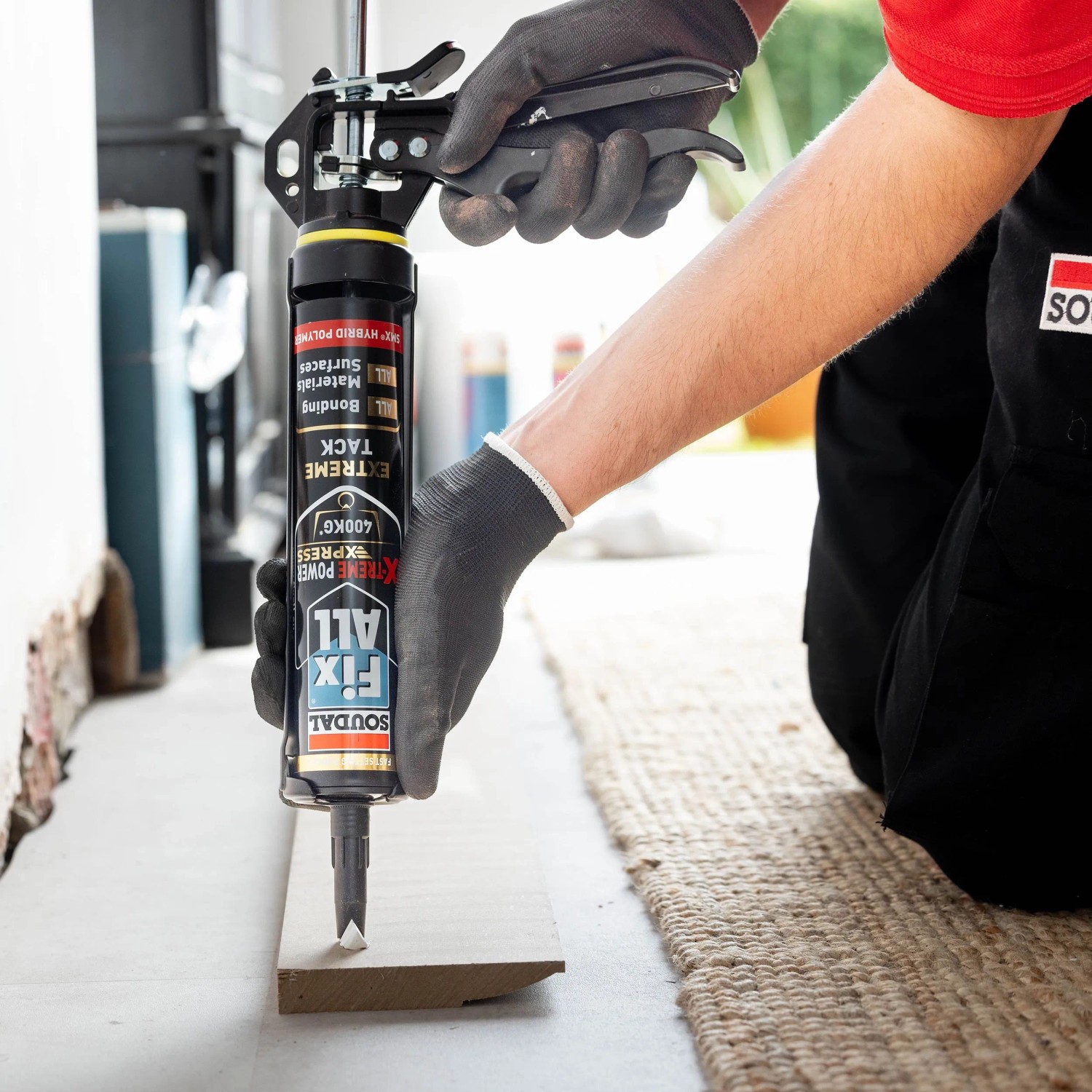 Person trägt Soudal Fix All X-Treme Power Montagekleber mit Kartuschenpistole auf Holzleiste auf. Hohe Haftung.