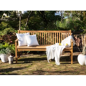 Beliani Gartenbank VIVARA aus Akazienholz, heller Holzfarbton mit Kissen und Decke im Garten.