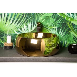 Goldenes Kerra Aufsatzwaschbecken KR-802 aus Sanitärkeramik auf Waschtischplatte, vor grüner Blatttapete.