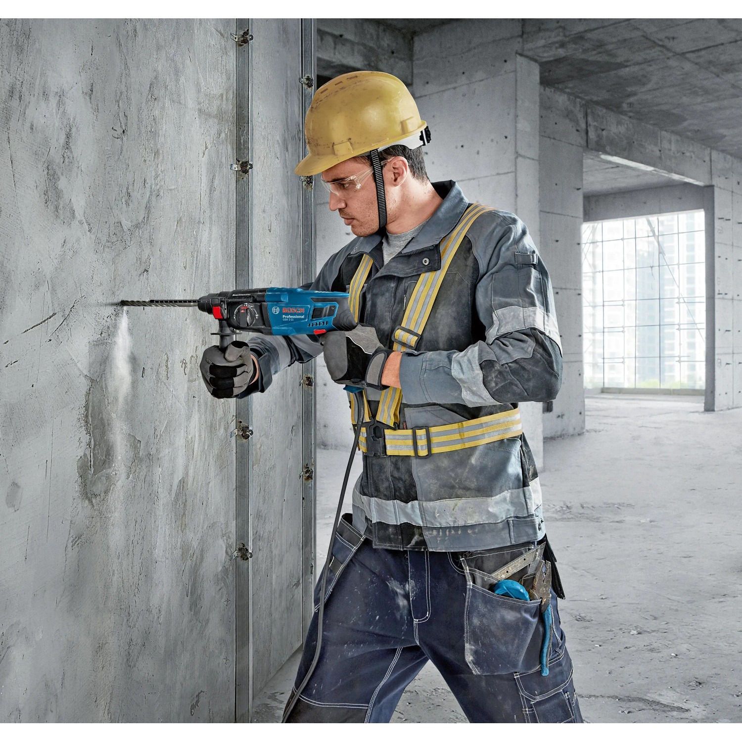 Bosch Professional GBH 2-21 Bohrhammer im Einsatz: Arbeiter bohrt mit dem blauen Bohrhammer in Betonwand.