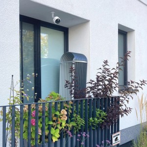 Weiße Kamera-Attrappe mit Blinklicht zur Sicherheitstechnik-Abschreckung an Hauswand.