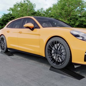 Gelbes Auto fährt auf zwei schwarze Wiltec Auffahrrampen aus PP. Ideal für Wartung, Nivellierung & tiefergelegte Fahrzeuge.