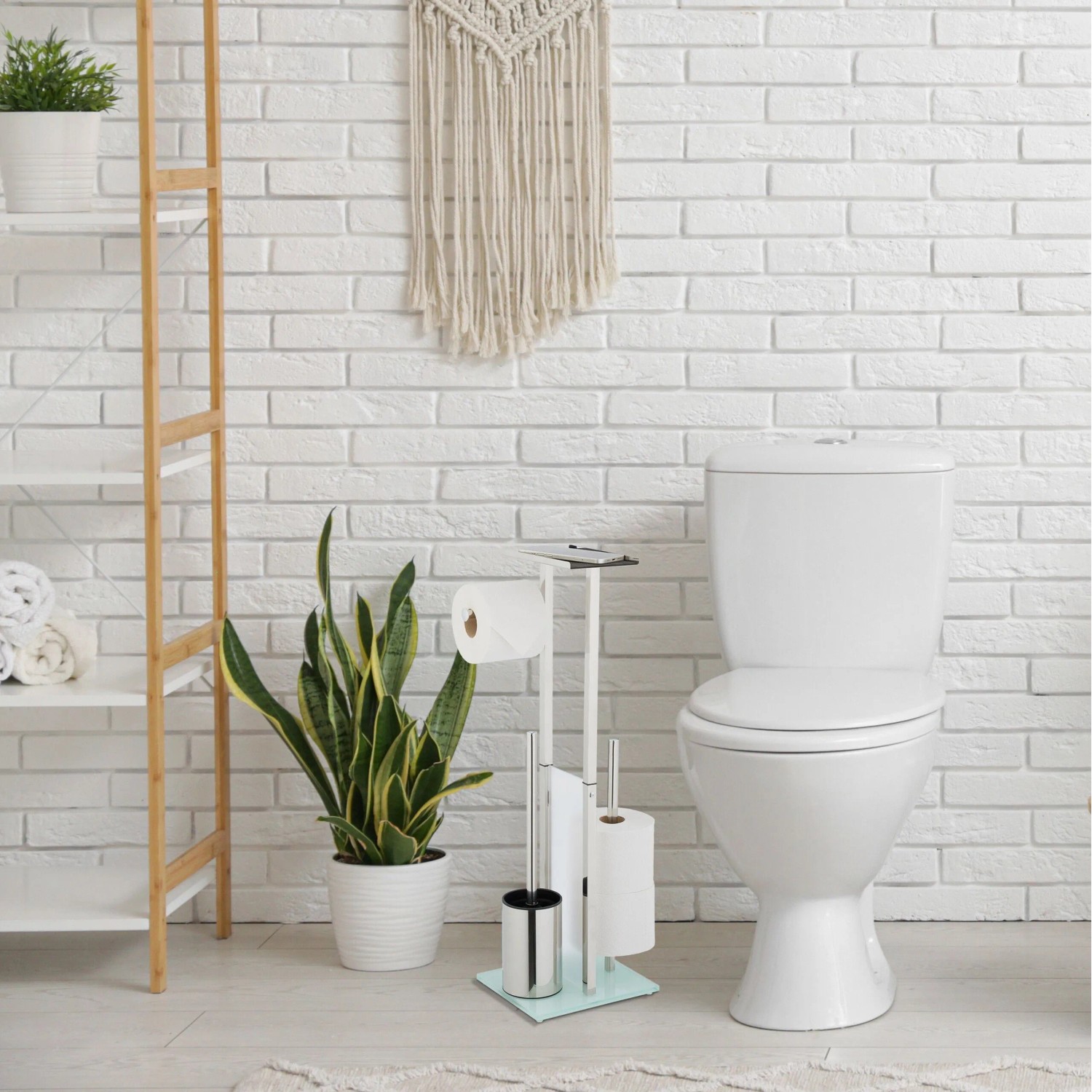 Moderne freistehende WC Garnitur aus Edelstahl mit Glasboden, Klorollenhalter, WC-Bürste und Ablage im Bad.
