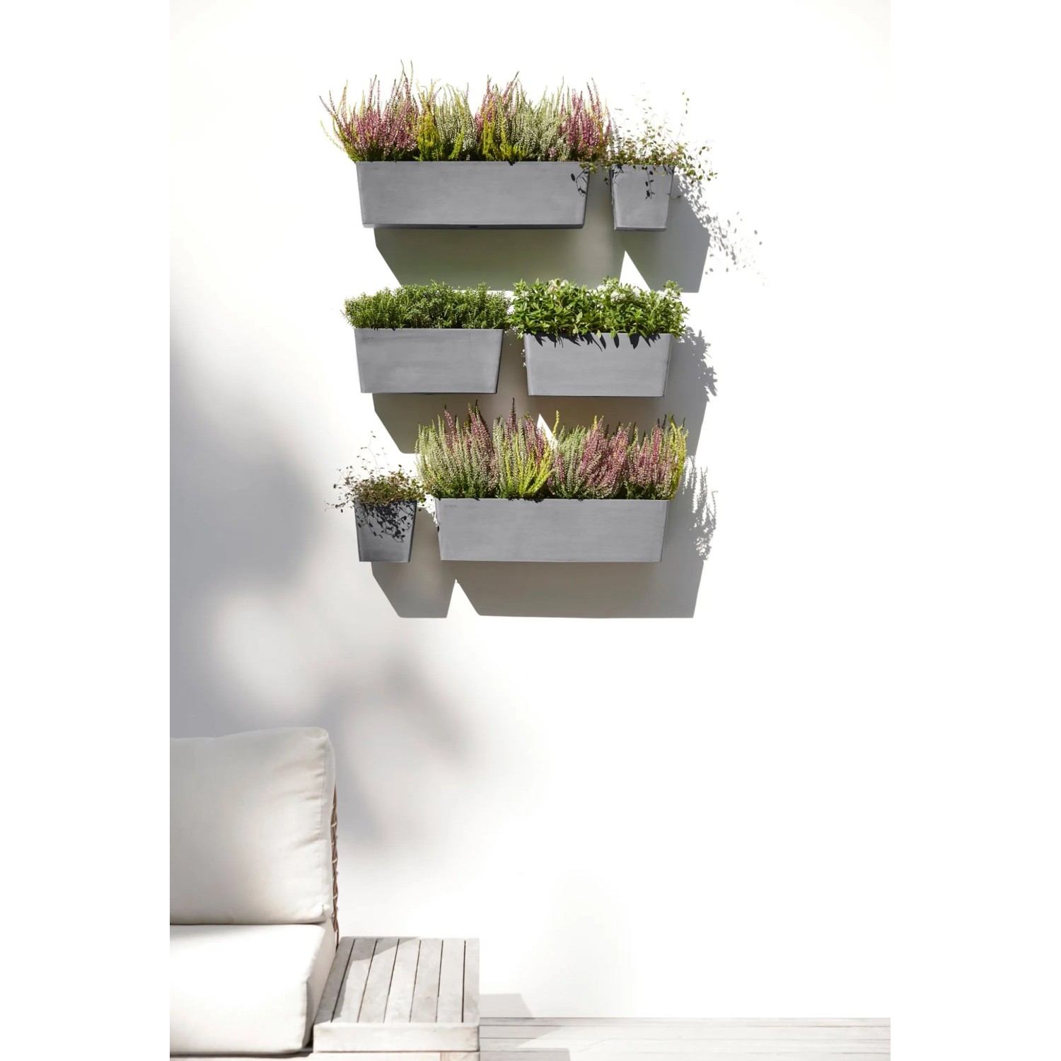 Ecopots Manhattan Wall Hängetöpfe in Grau, bepflanzt an einer weißen Wand.