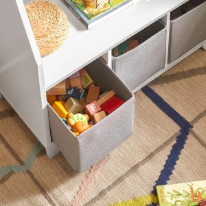 Weißes Kinder Bücherregal mit Ablagen und Aufbewahrungsboxen, gefüllt mit Spielzeug.