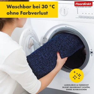 Waschbare, dunkelblaue Floordirekt Badematte Nasa wird in eine Waschmaschine gelegt.