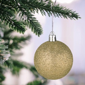 Glitzernde champagnerfarbene Weihnachtskugel aus Polystyrol am Christbaumzweig. Festlicher Baumschmuck.