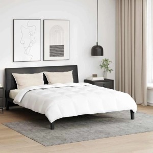 Weiße gesteppte Winterbettdecke mit zwei Kissen auf einem Bett in modernem Schlafzimmer. Daunenfeder-Set.