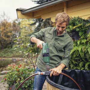 Mann bedient Gardena Bohrmaschinenpumpe am Gartenteich. Elektro-Pumpe mit Bohrmaschinen-Antrieb.