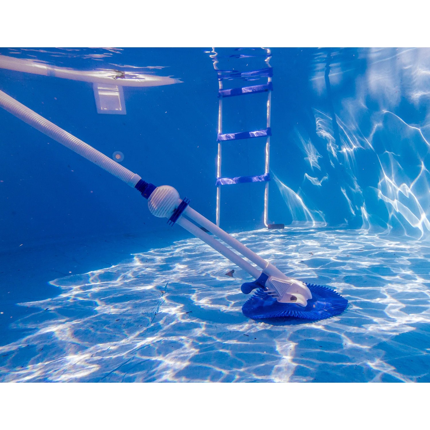 Weißer Gre Automatik-Poolreiniger im Pool unter Wasser mit Poolleiter im Hintergrund.