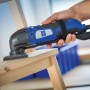 LUX Exzenterschleifer mit Delta-Schleifscheibe im Einsatz auf Holz, blau-schwarzes Design.
