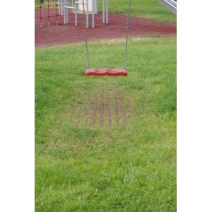 Rote Rasengitter-Fallschutzplatte 100x100x4,5 cm unter einer Schaukel auf Rasen.