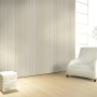 Glööckler Vliestapete Imperial Welle in Champagner-Metallic an Wand, kombiniert mit weißem Sessel.