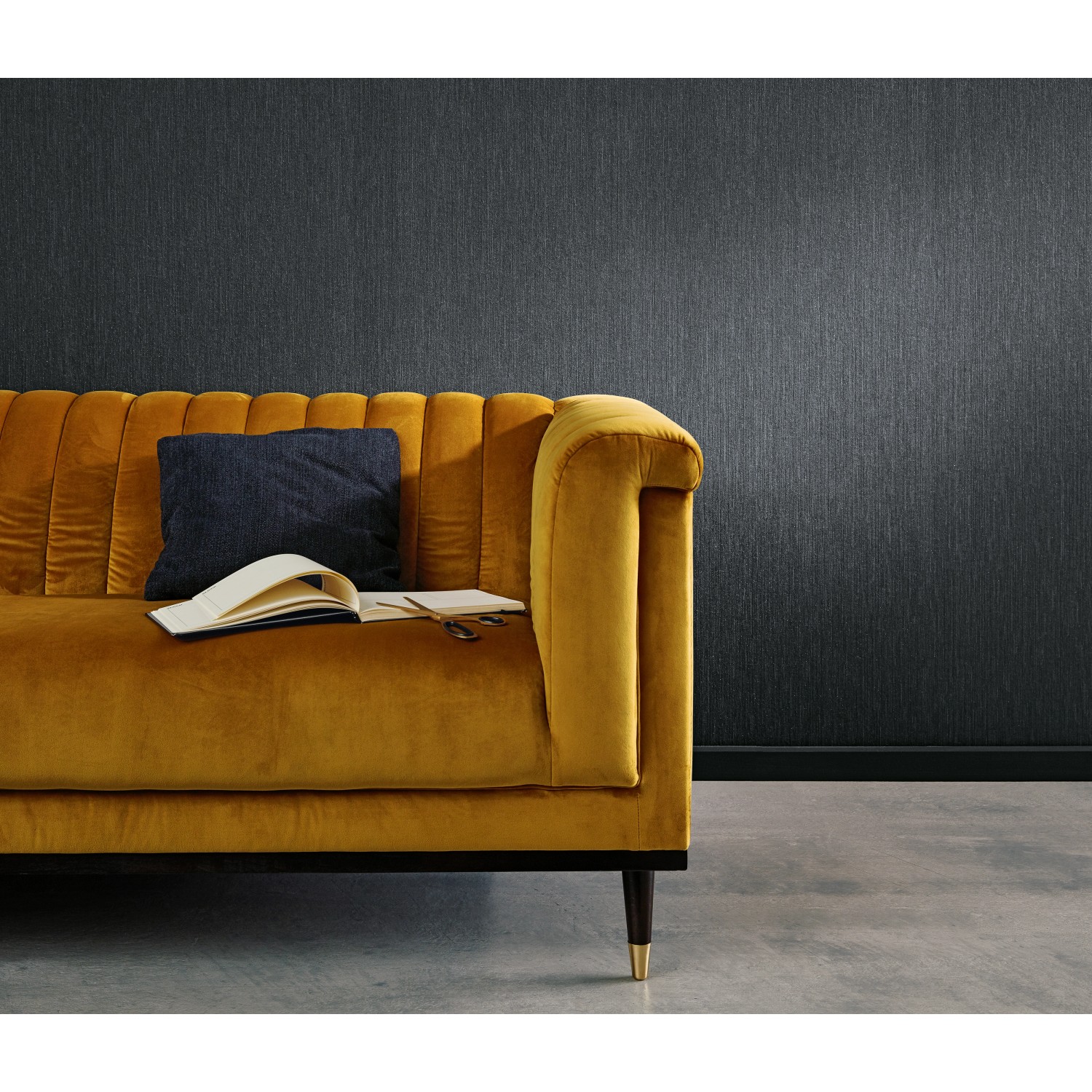 Schwarze Erismann Vliestapete Uni von Guido Maria Kretschmer an Wand hinter Sofa.