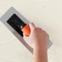 Hand mit Alpina Effekt Kelle für Putz- und Strukturfarben an Wand.