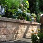 Bruchsteinmauer Halbelement in Sandsteinfarben, Teil einer Gartenmauer mit Pflanzen.