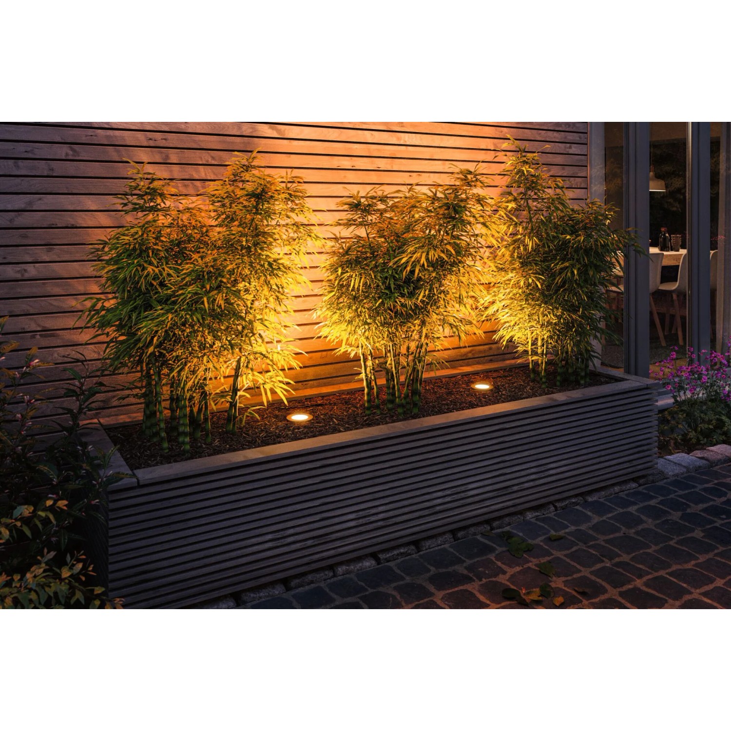 Paulmann LED Bodeneinbaustrahler Floor Plug & Shine beleuchtet Pflanzen im Beet mit warmweißem Licht.