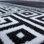 Detailansicht des schwarzen Kurzflorteppichs Ayyildiz Parma mit weißem, geometrischem Muster.