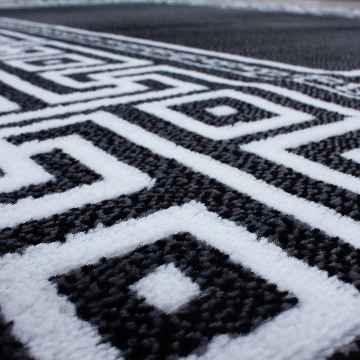 Detailansicht des schwarzen Kurzflorteppichs Ayyildiz Parma mit weißem, geometrischem Muster.