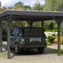 Skan Holz Carport Spessart, schiefergrau, mit Auto. Einzelcarport mit Flachdach und sechs Pfosten.