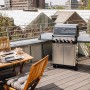 Enders Gasgrill Monroe Pro 3 SIKR Turbo auf einer Dachterrasse mit Tisch und Stühlen.